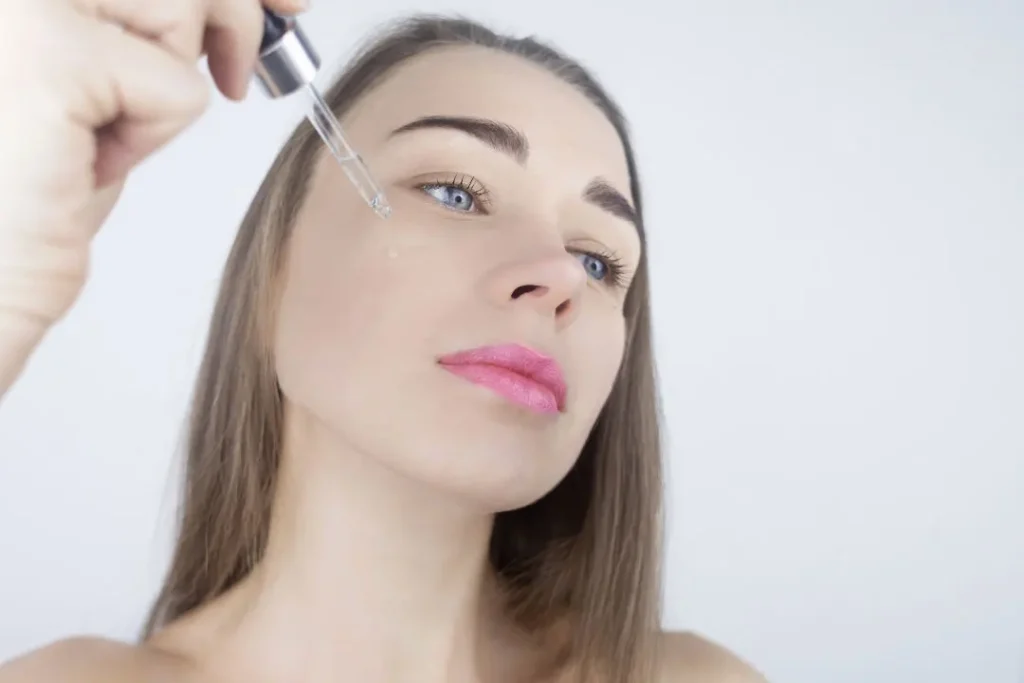 A woman applying CDB oil on her face.