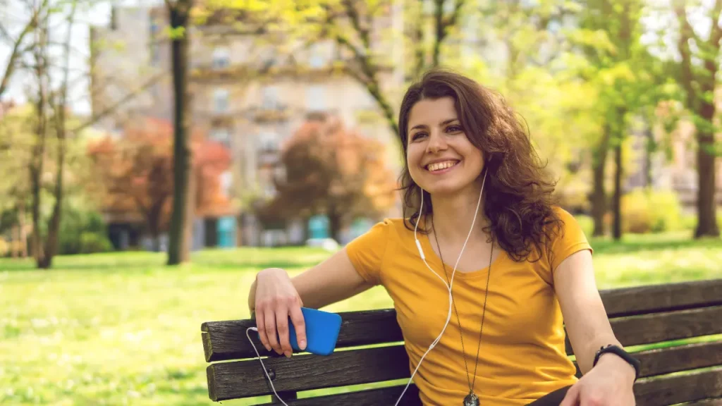 Young happy girl smiling while listening songs in a garden