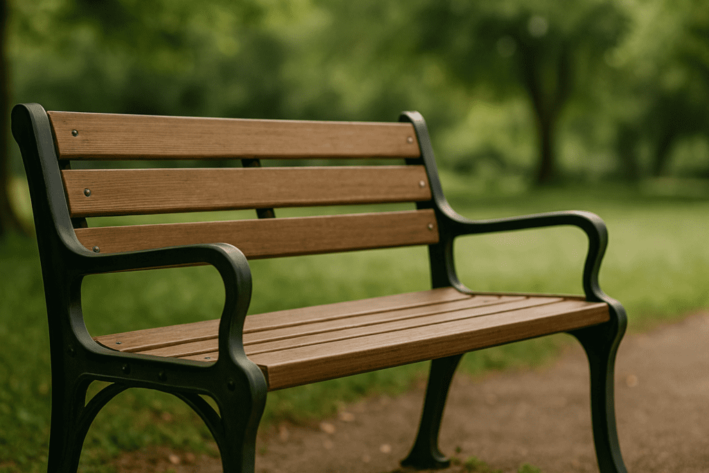 Wooden park bench with metal frame in daylight, surrounded by softly blurred green trees and grass